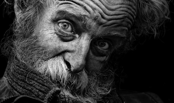 A stark black and white portrait of an elderly man in a bustling Indian market, his eyes reflecting years of stories.