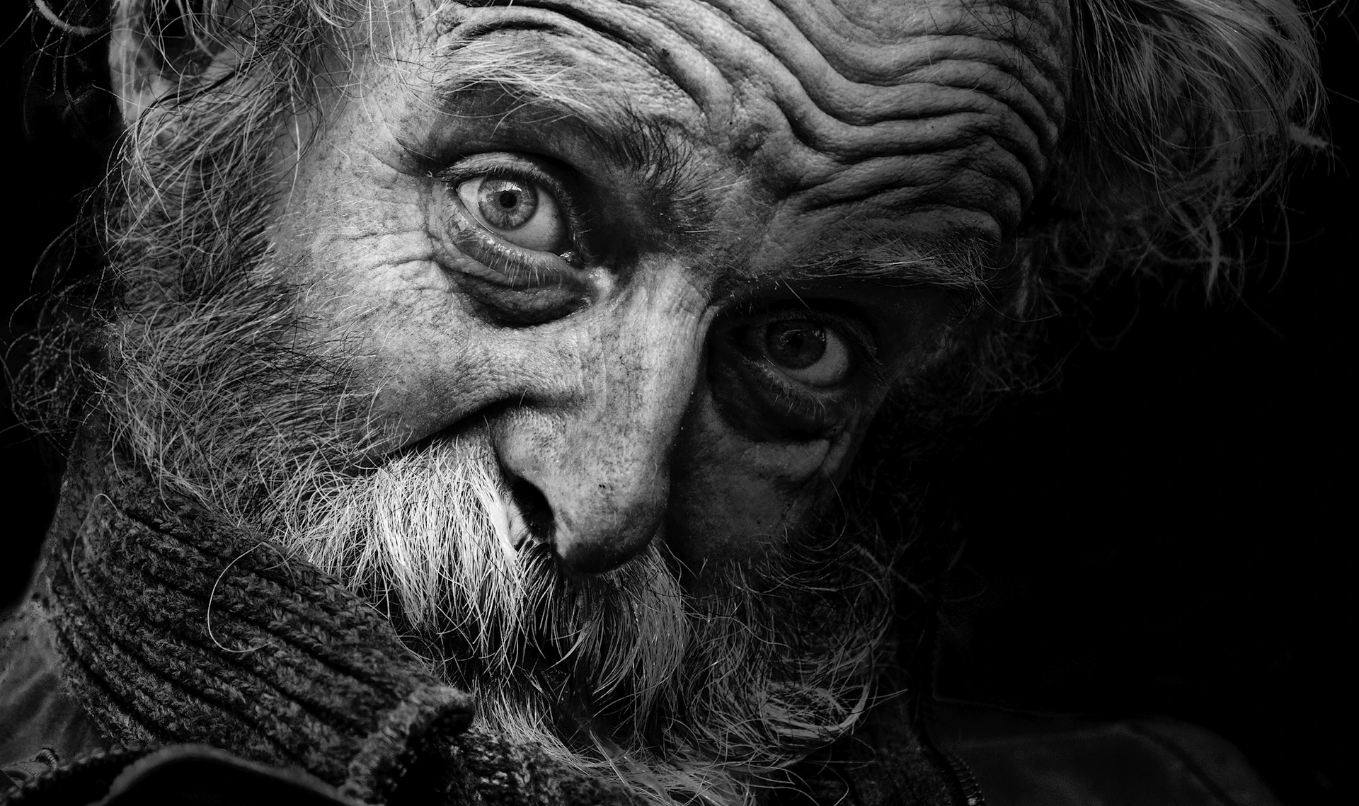 An artistic black-and-white shot of an elderly man with deep lines of experience etched on his face, telling a silent story.
