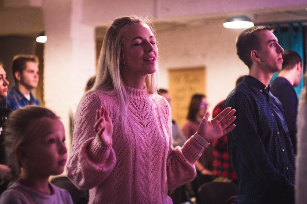 woman in whit sweater standing with her hand raised