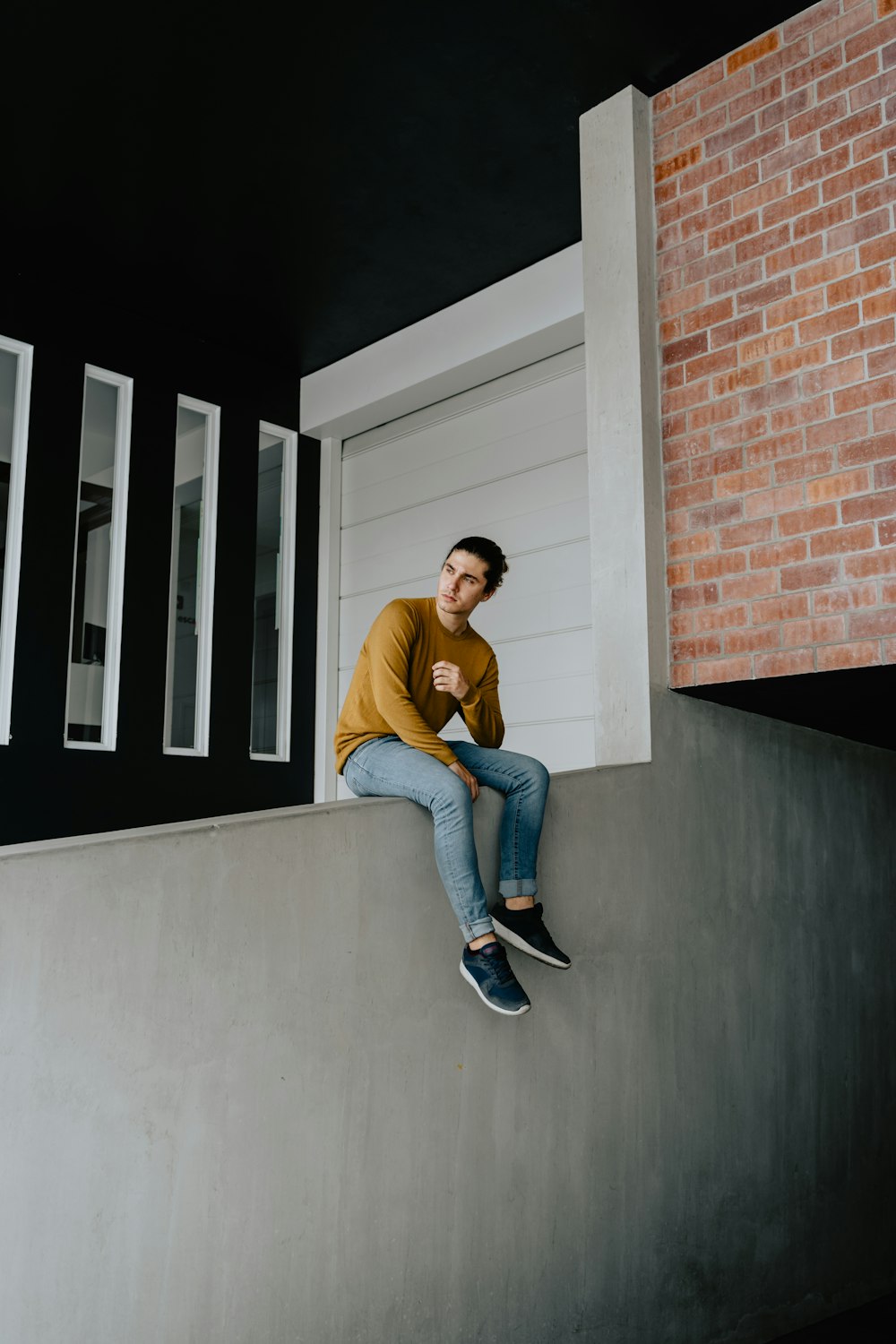 man sitting on gray wall