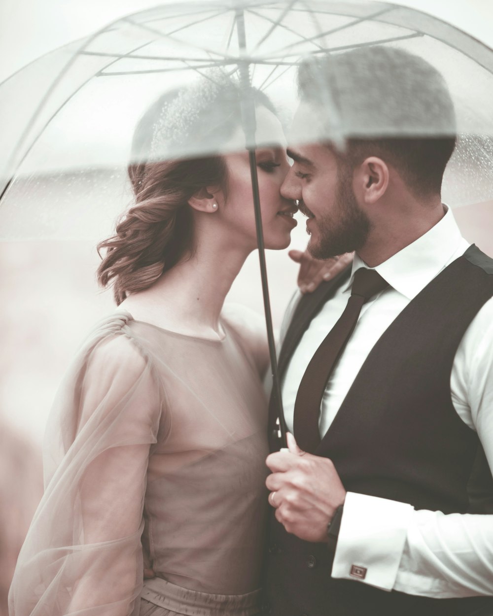 Frau und Mann wollen sich unter dem Regenschirm küssen
