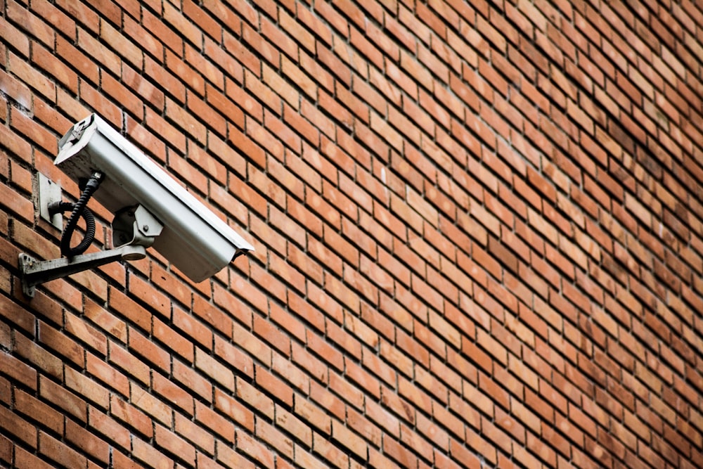 white CCTV on brown brick wall