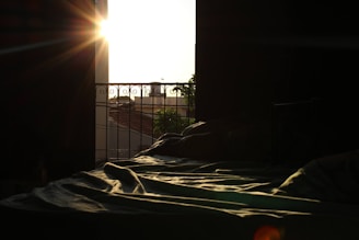 Morning light filtering through sheer curtains onto a rumpled bed with a half-opened poetry book.