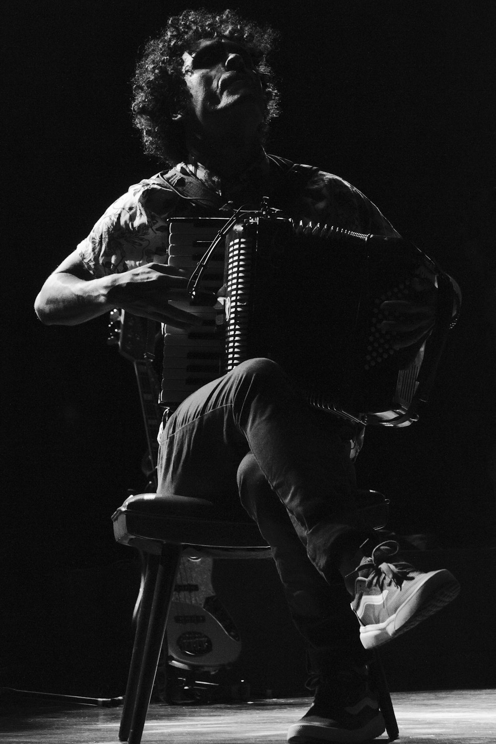 man sitting on chair playing accordion