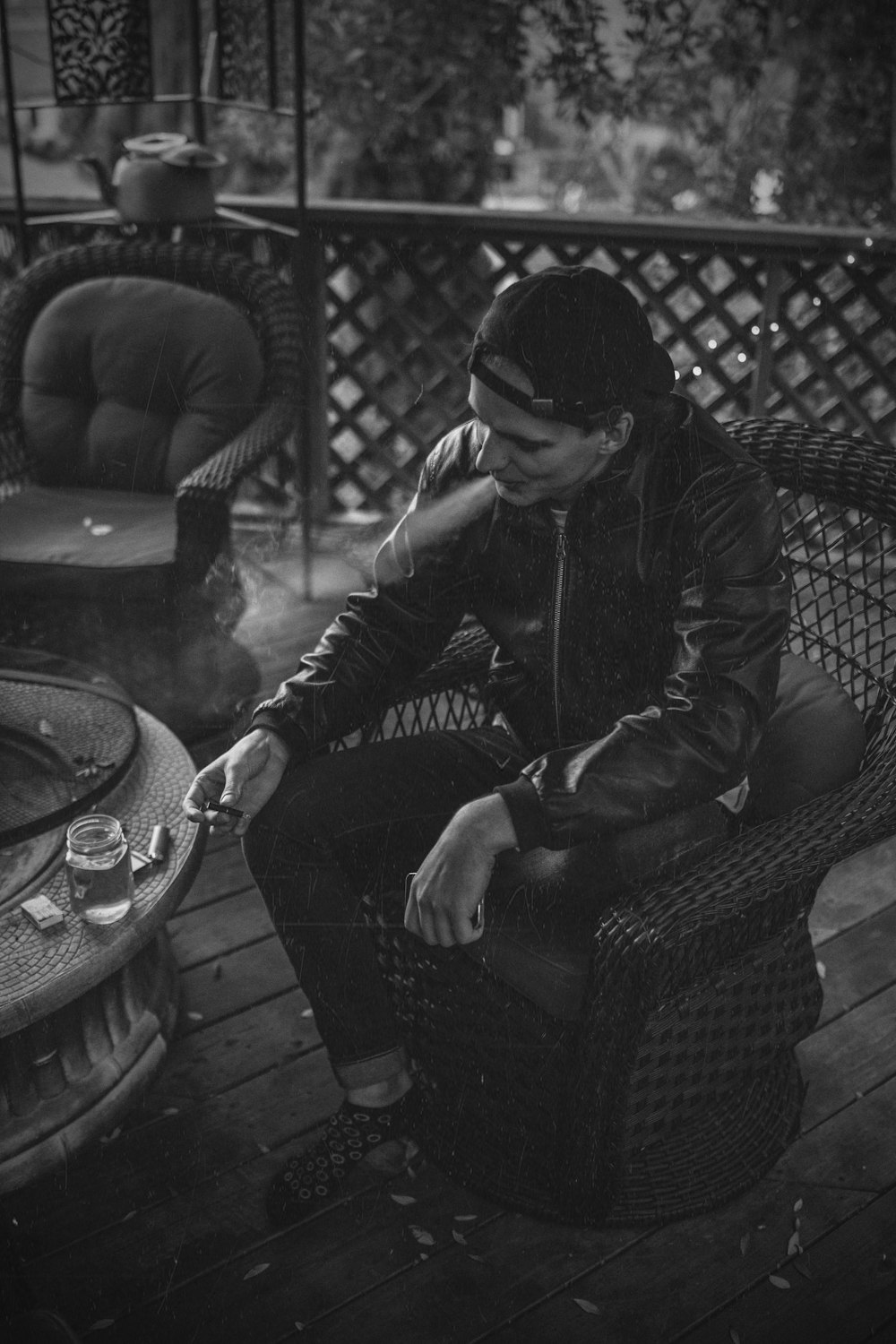Fotografía en escala de grises de un hombre sentado en la silla fumando