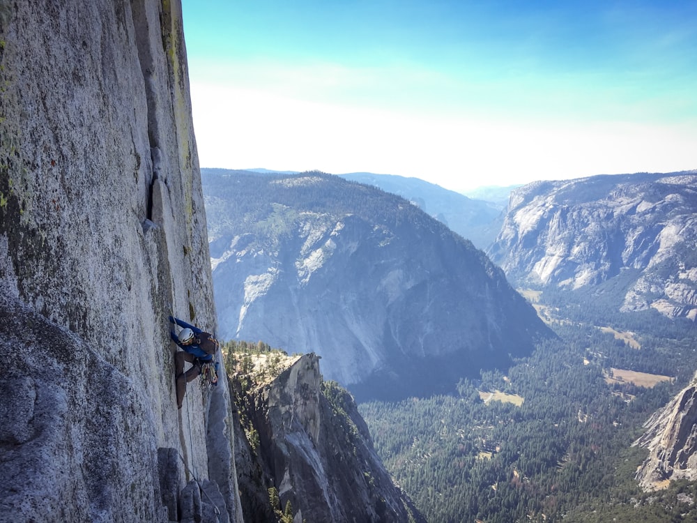 person climbing on rock formation during daytime