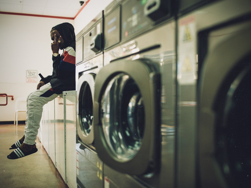 man sitting on laundry appliances