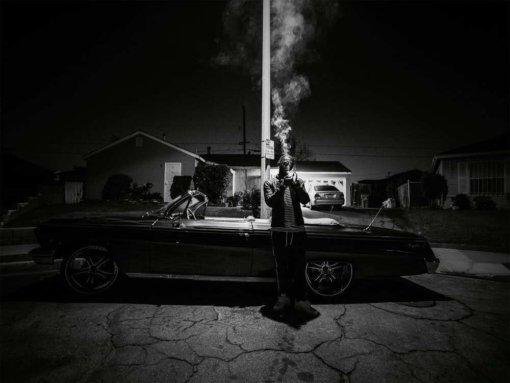man smoking standing beside convertible coupe