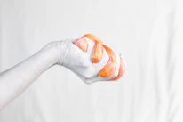 Close-up of hands gently squeezing a soft, fruit-shaped squishy toy.