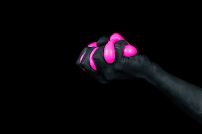 selective color photography of hand holding pink balloon