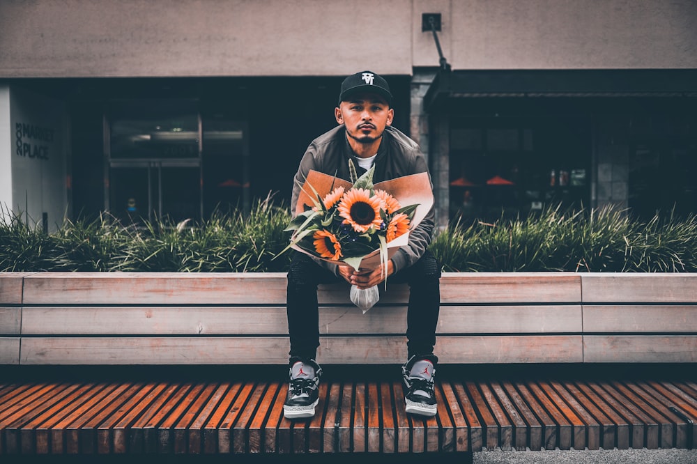 sitting man holding sunflower bouquet