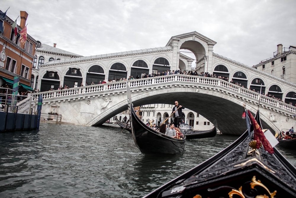 man riding gondola boat under Rialto Bridge, Italy
