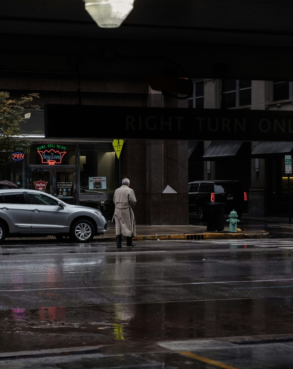 man in gray coat crossing the road near gray vehicle