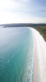 A serene beach with crystal clear waters and lush greenery, inviting relaxation and exploration.