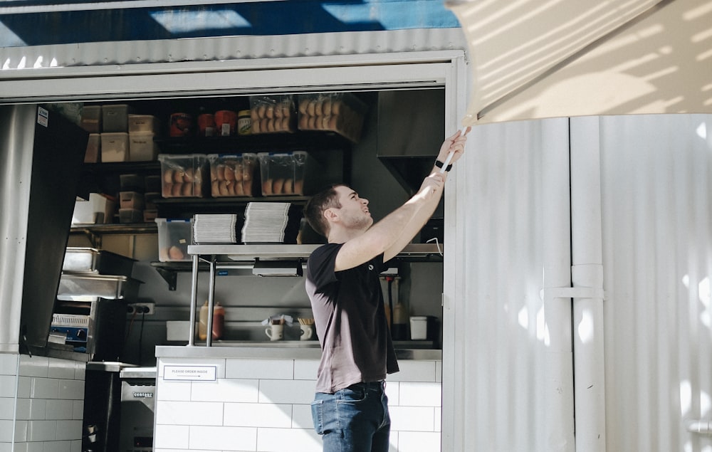 man wearing black shirt standing near the cabinet