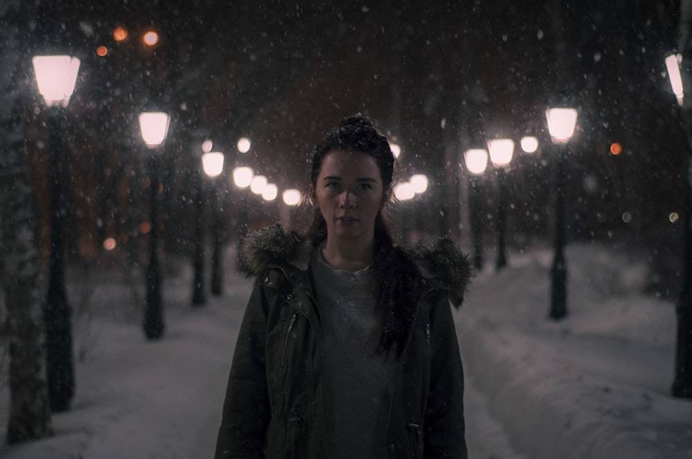 Selektive Fokusfotografie einer Frau, die auf einem Schneefeld steht