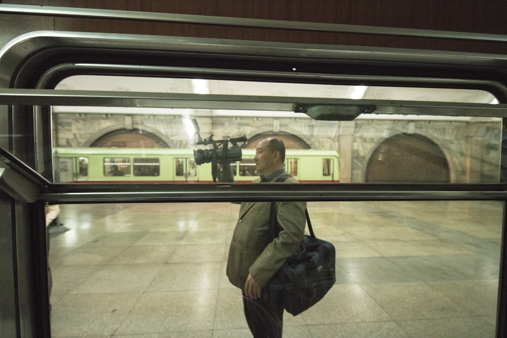 man in brown jacket with black duffel bag holding professional camera