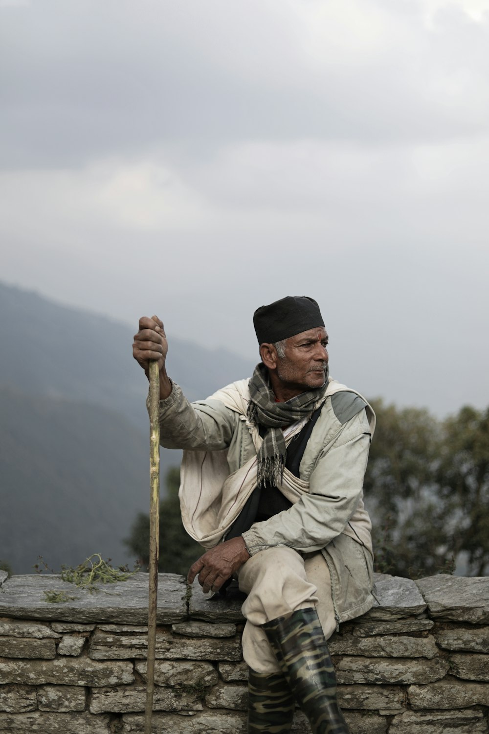 man in black cap and beige suit holding stick