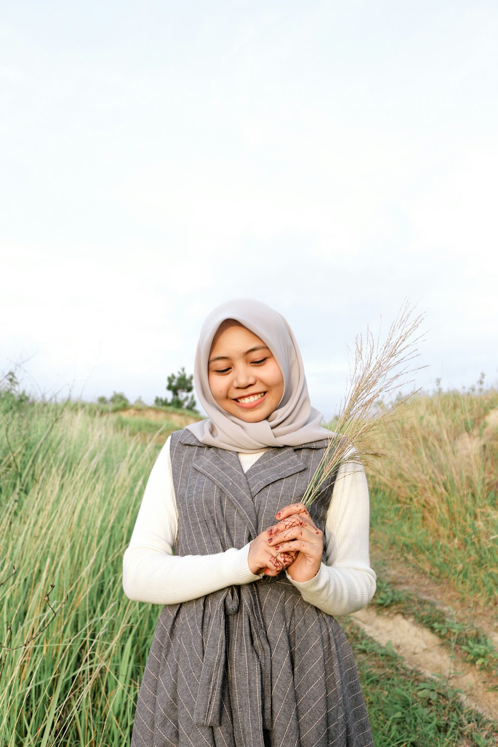 smiling woman holding grass during daytime