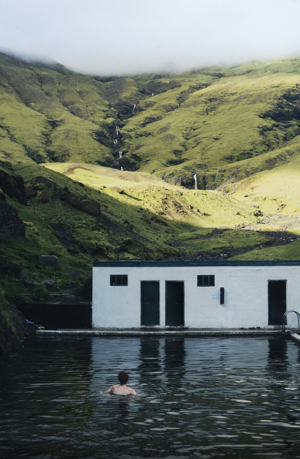 person on body of water near mountain during daytime