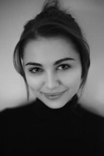 A close-up portrait of Mia Milandori with soft lighting highlighting her serene expression against a dark background.
