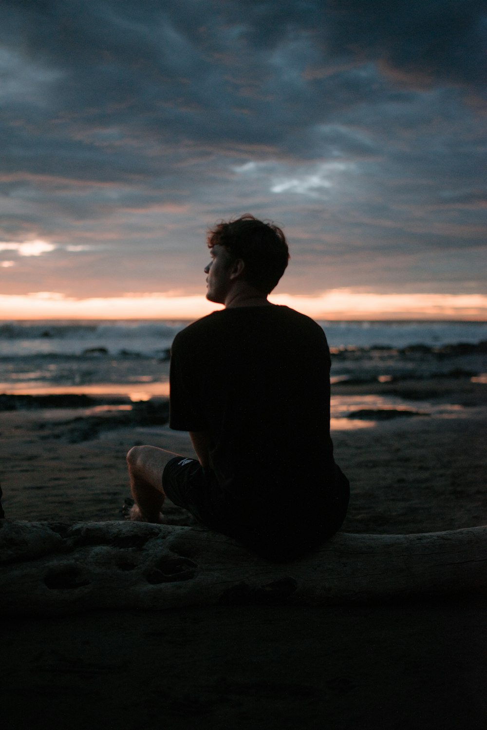 Foto de la silueta del hombre sentado en la playa