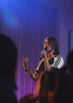 woman in black and white t-shirt singing on stage