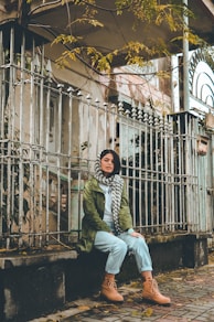 woman sitting on white fence near house during daytime