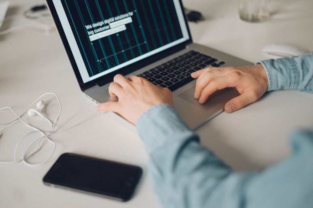 selective focus photography of person about to touch MacBook