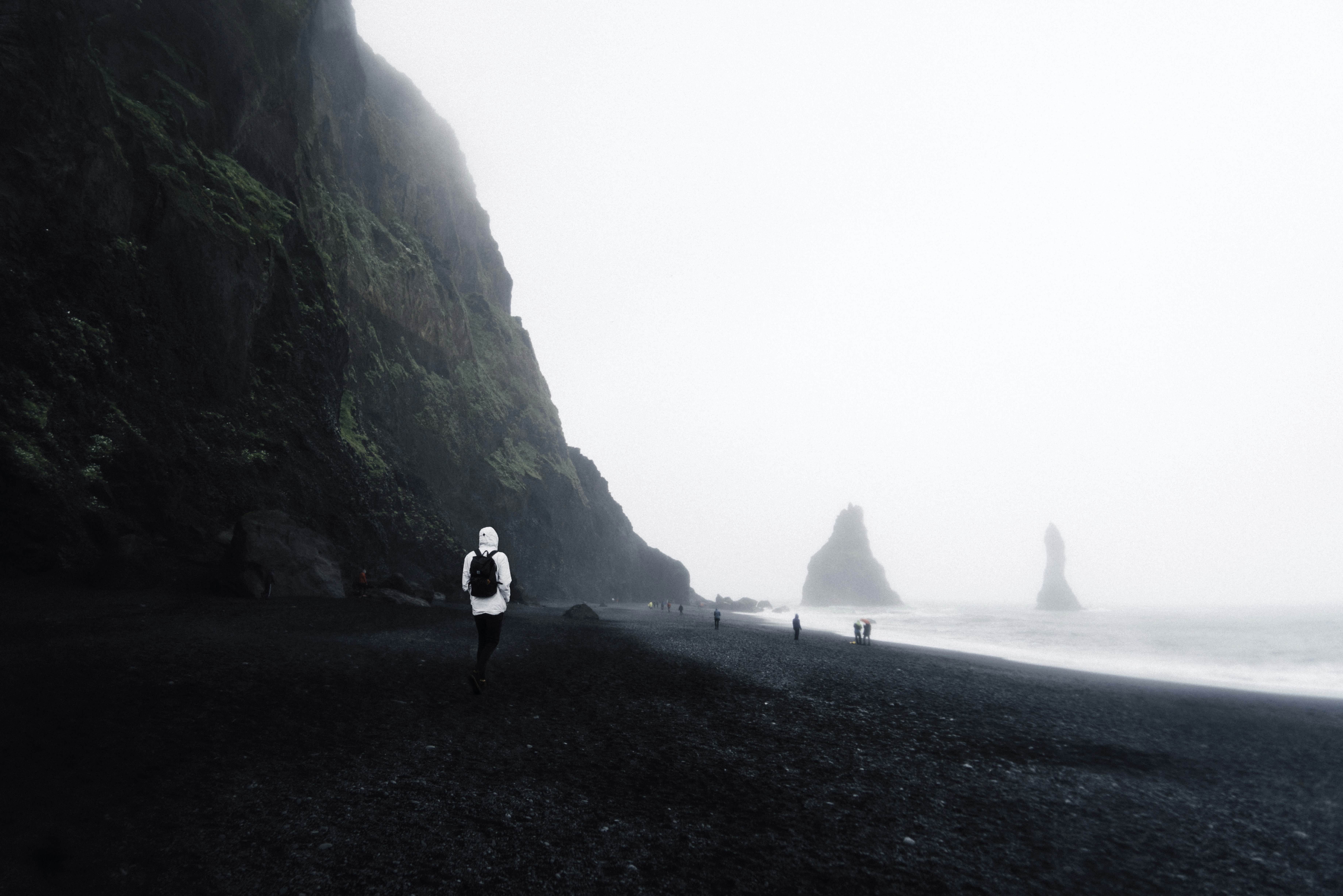 personne portant un sweat à capuche blanc debout sur le sable