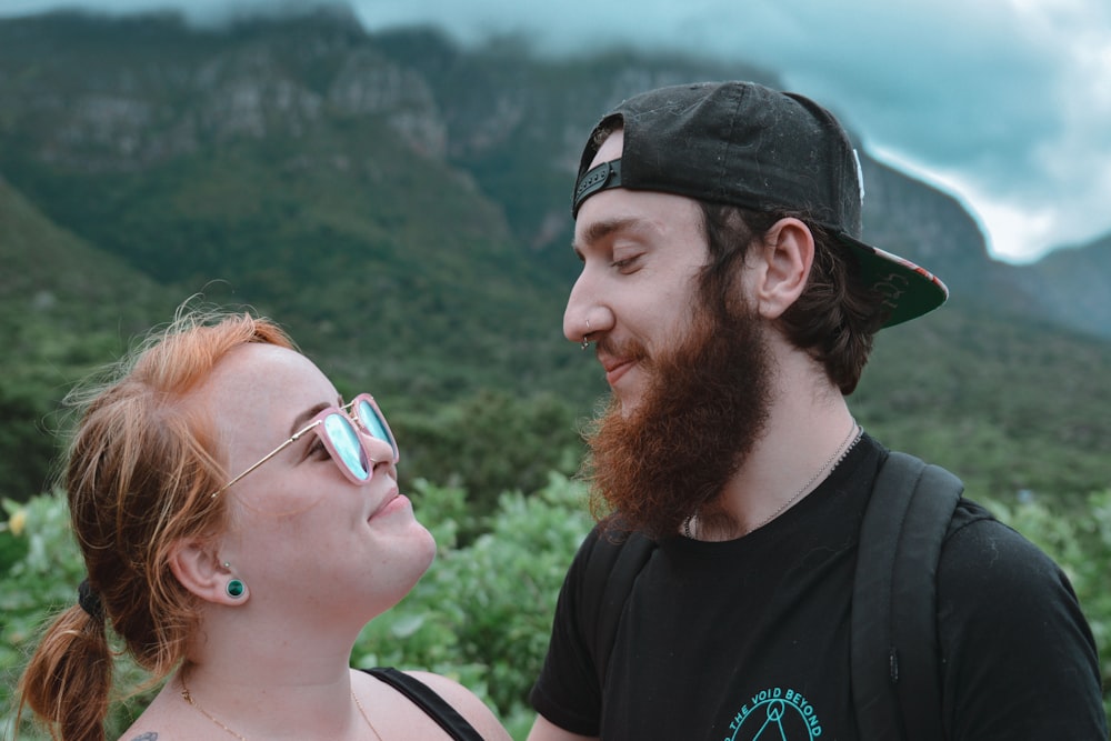 man and woman looking each other while smiling with mountain view