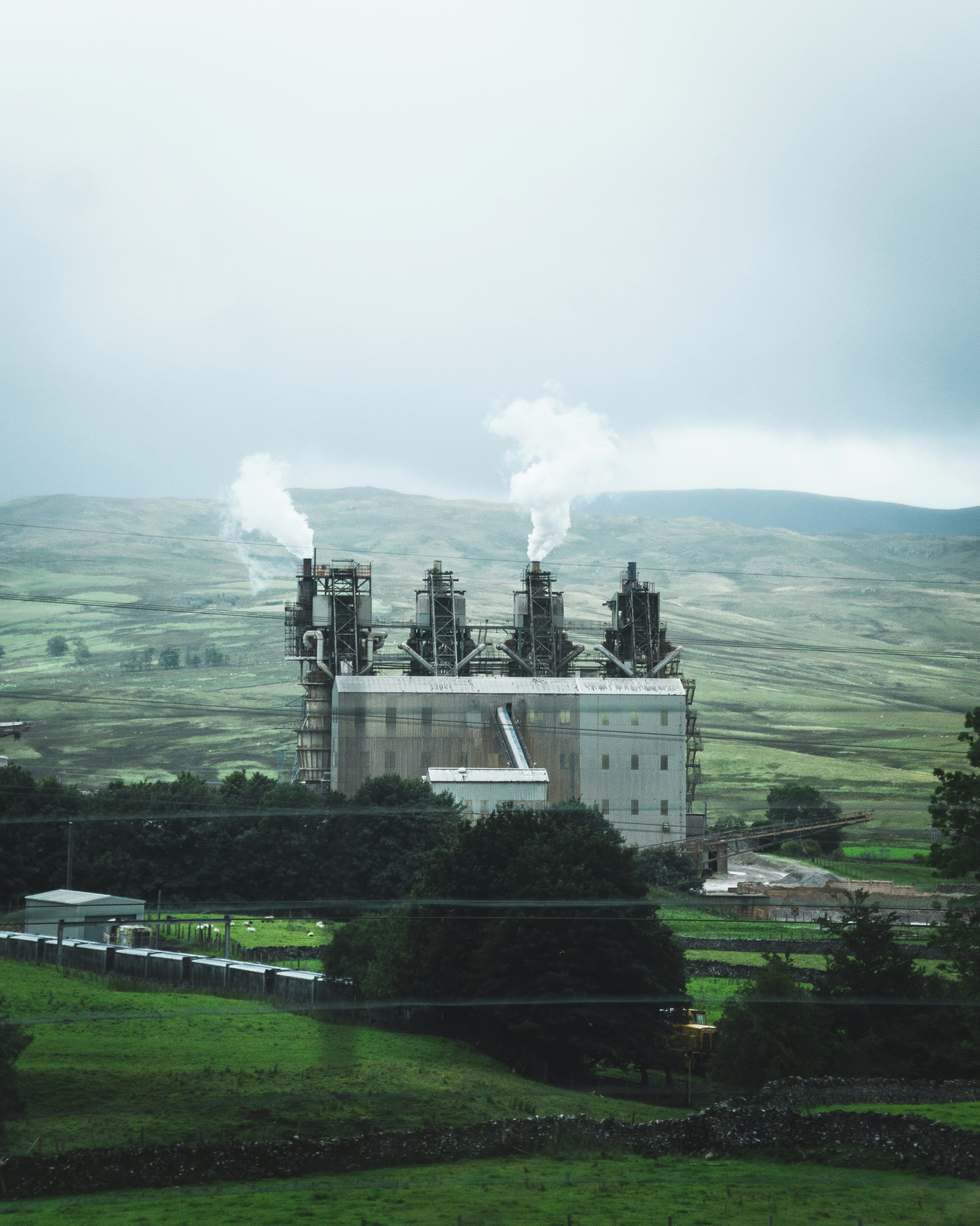 Bâtiment en béton blanc sur un champ d’herbe verte près de la montagne sous des nuages blancs pendant la journée