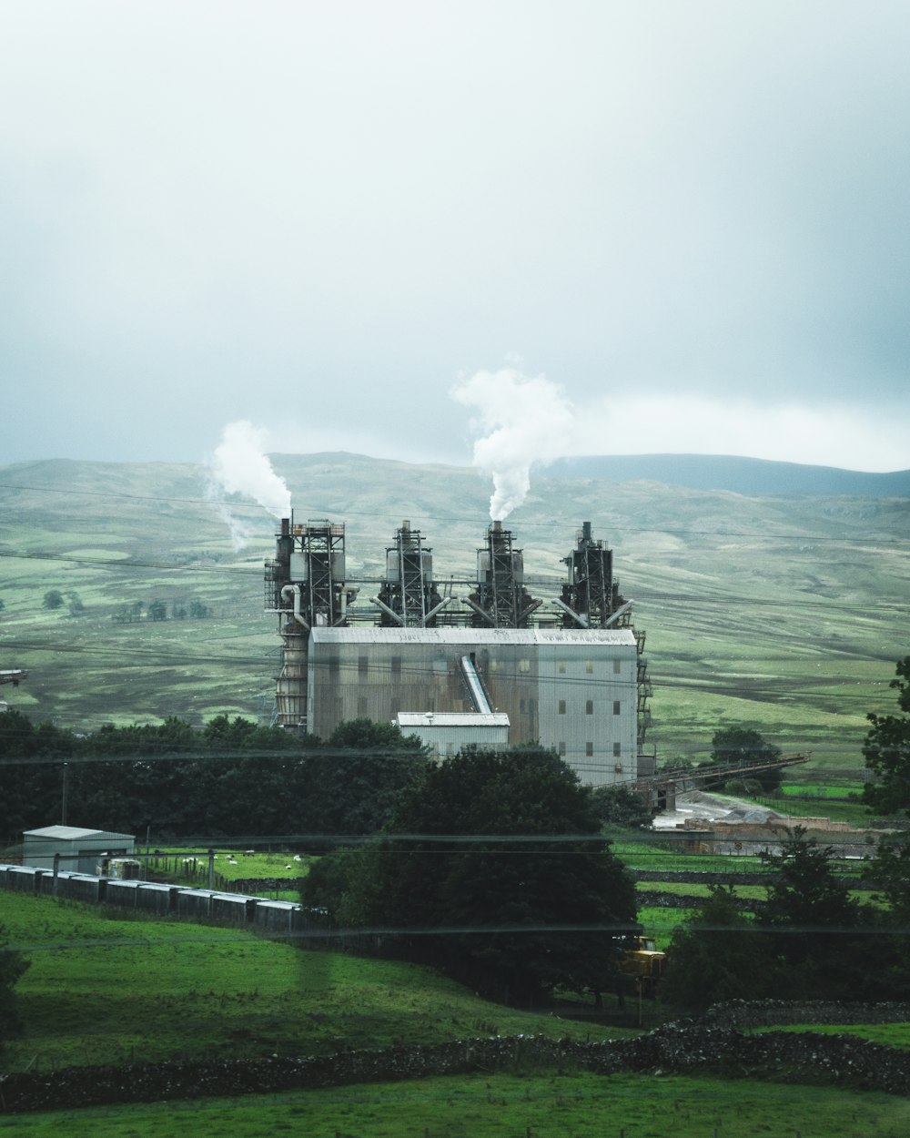 edificio de hormigón blanco en el campo de hierba verde cerca de la montaña bajo nubes blancas durante el día