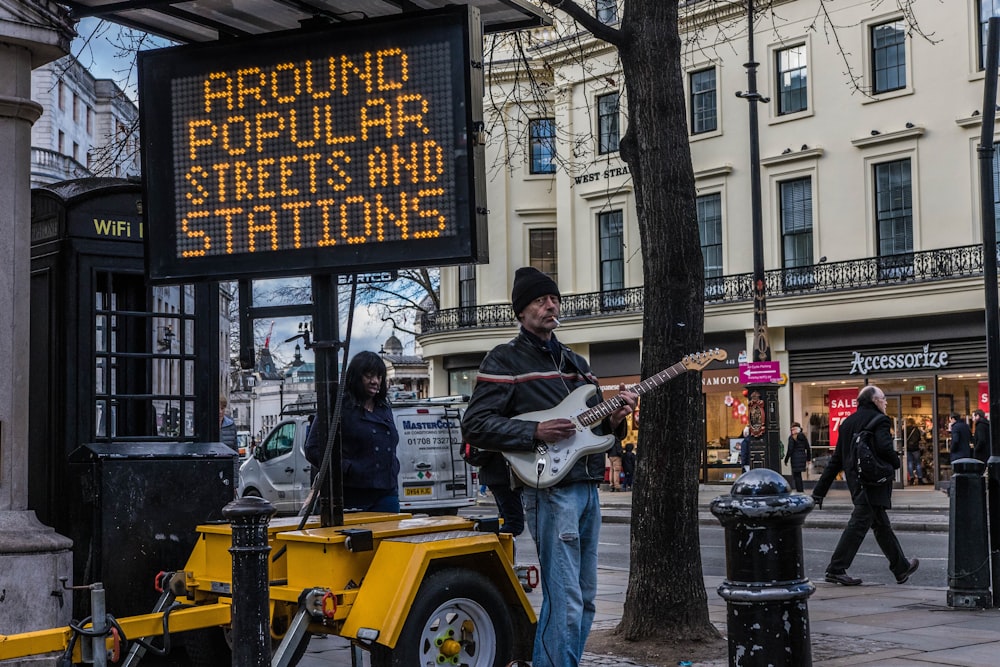 man playing guitar near LED signage