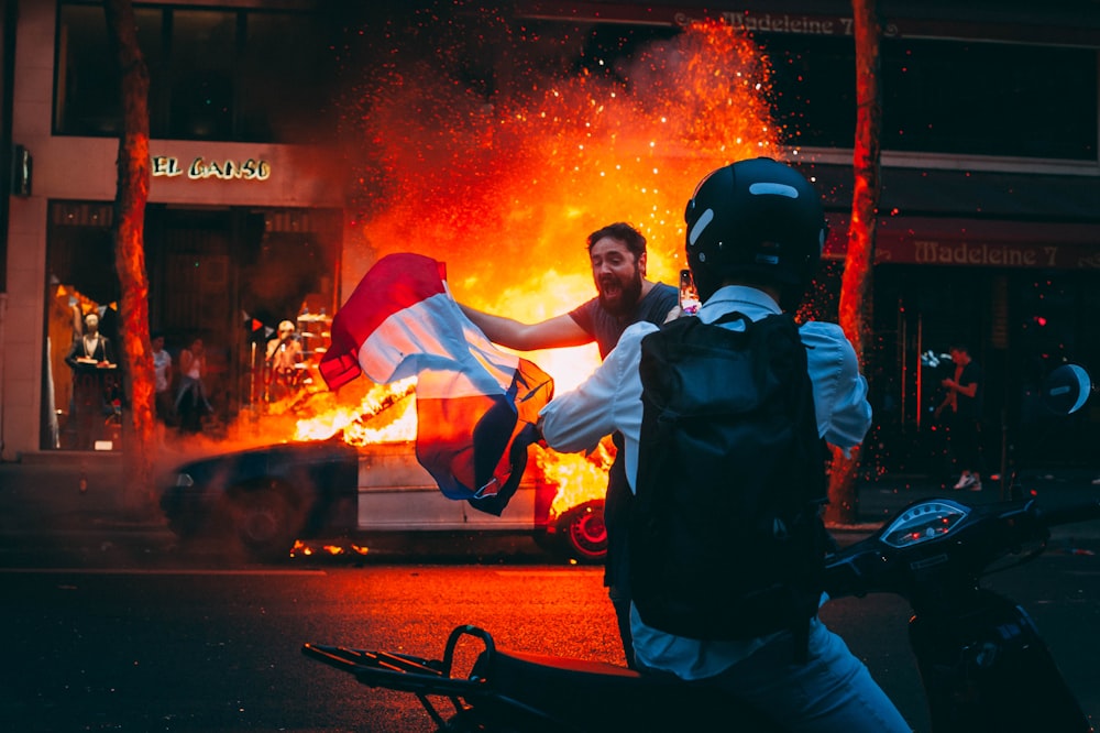 men in front of burning car