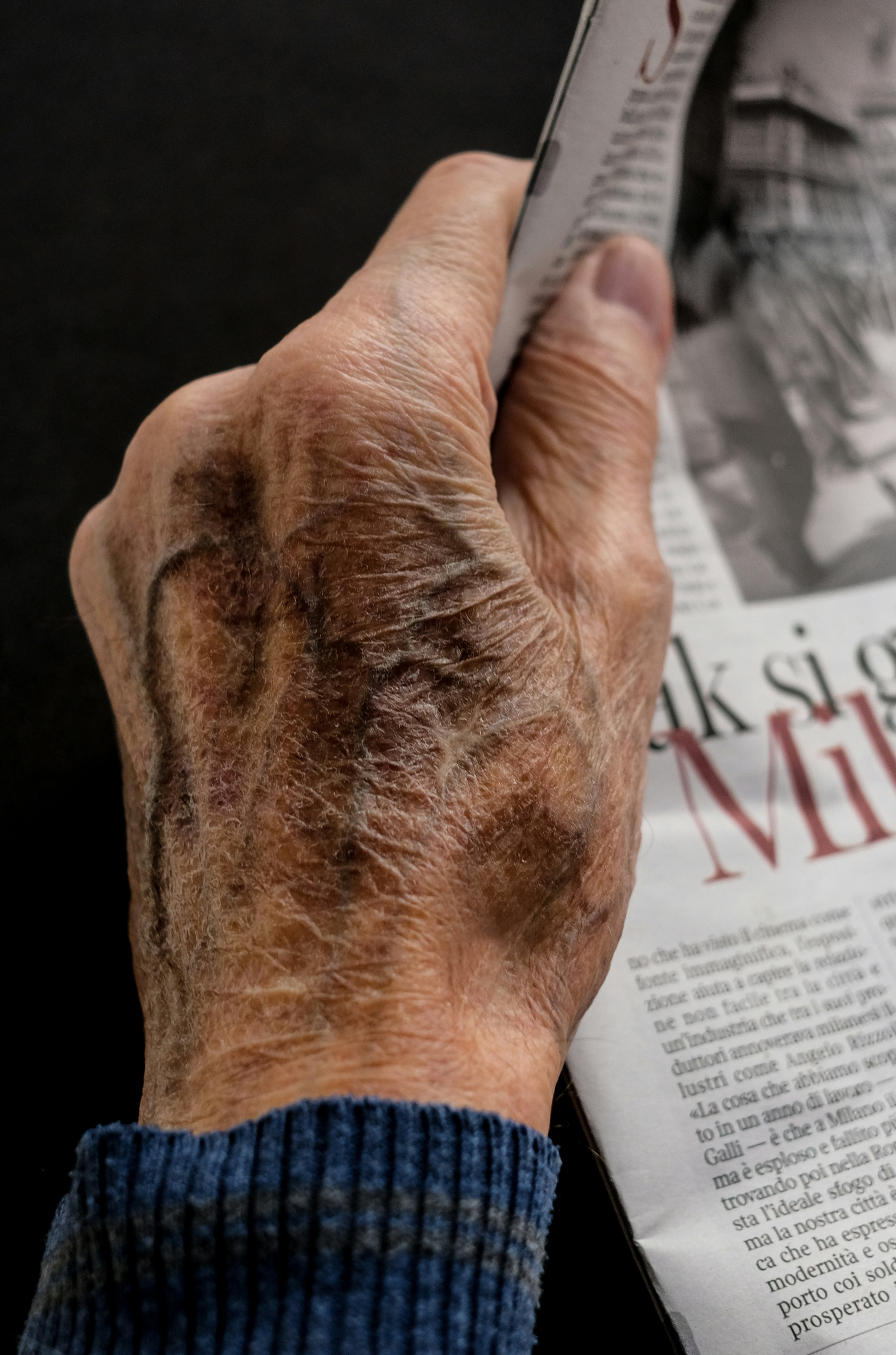 man wearing blue long sleeve top holding newspaper