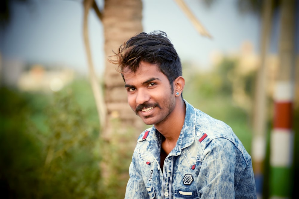 selective focus photography of smiling man wearing blue denim jacket