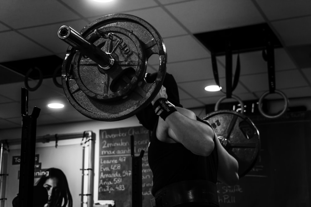 grayscale photo of man lifting barbell