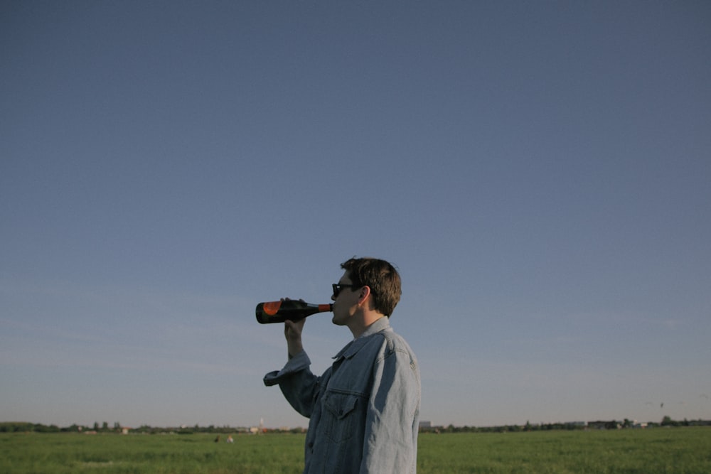 man drinking in bottle under gray sky