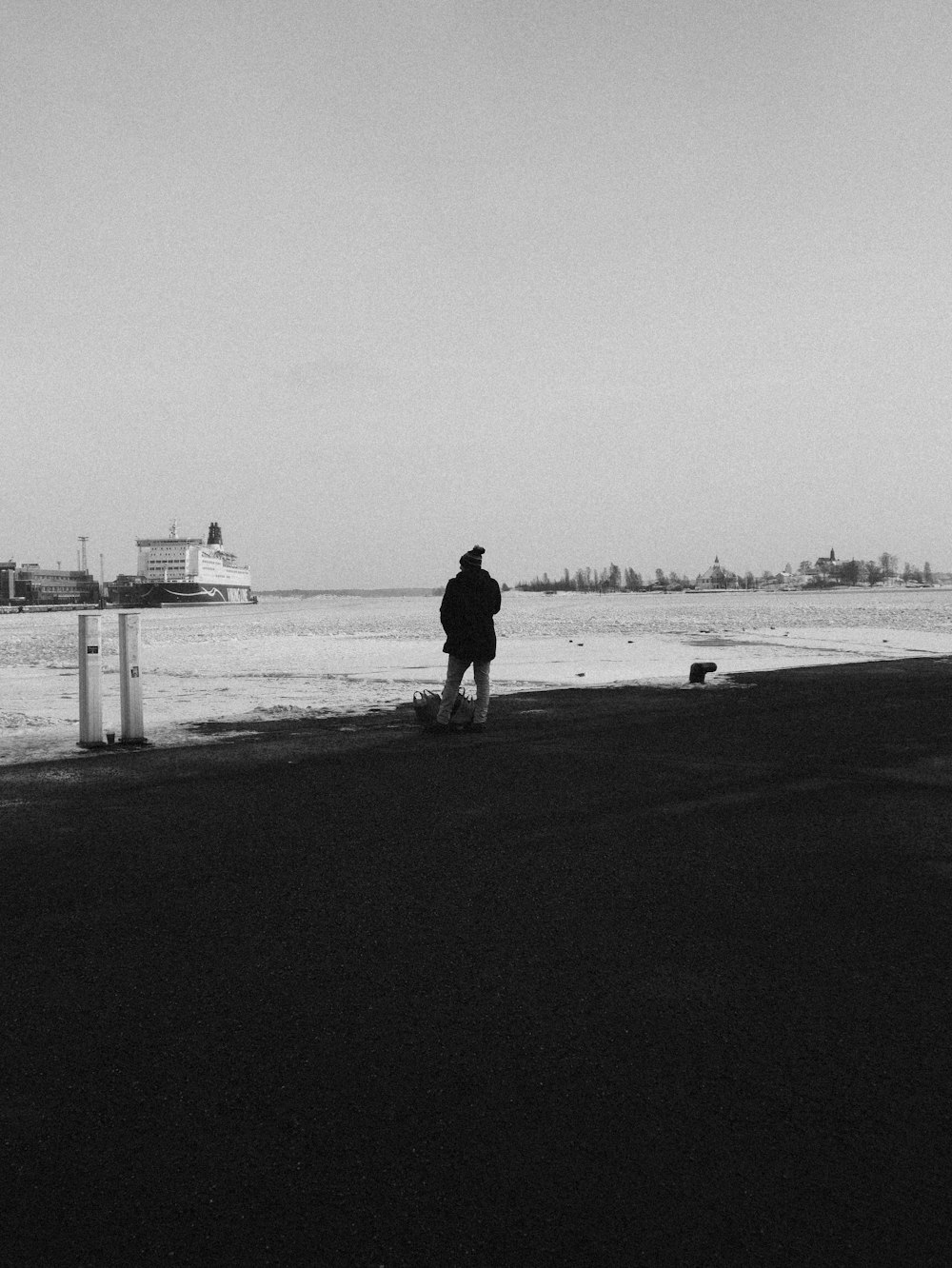 grayscale photography of man standing on seashore