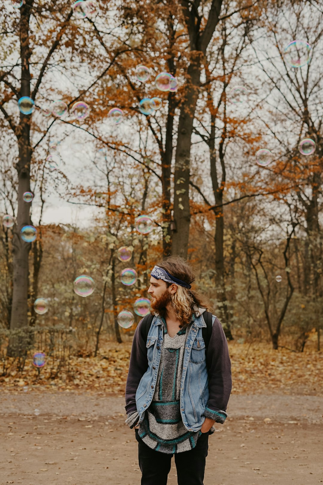 man in blue and black jacket standing near tree during daytime