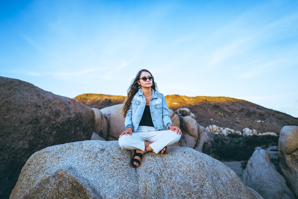 woman sitting on rock under clear blue sky