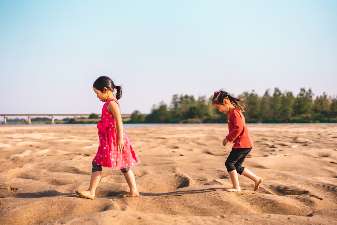 two girl walking on sand during daytime