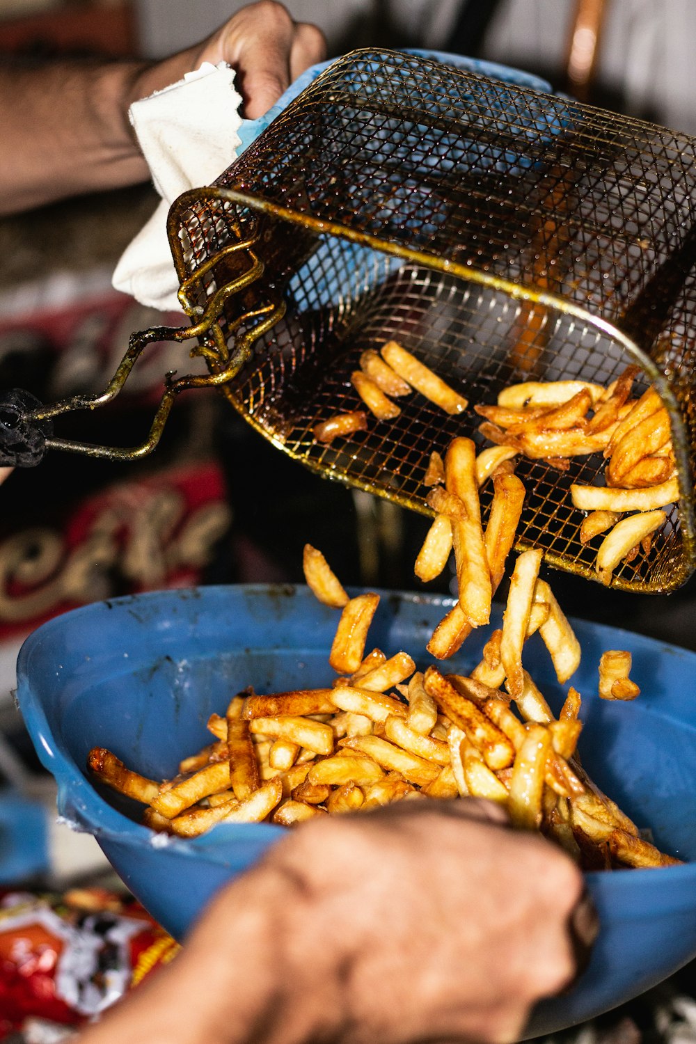 person transferring fries from basket to a bowl