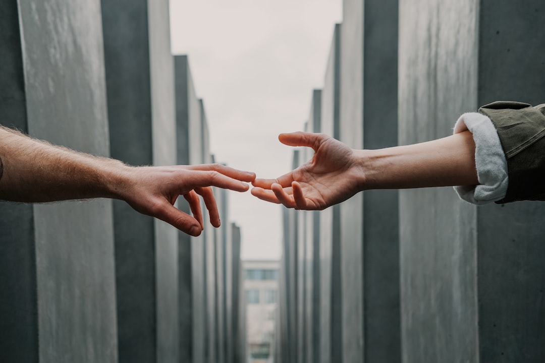 Hands reaching towards each other with fingertips touching across the gap between two buildings