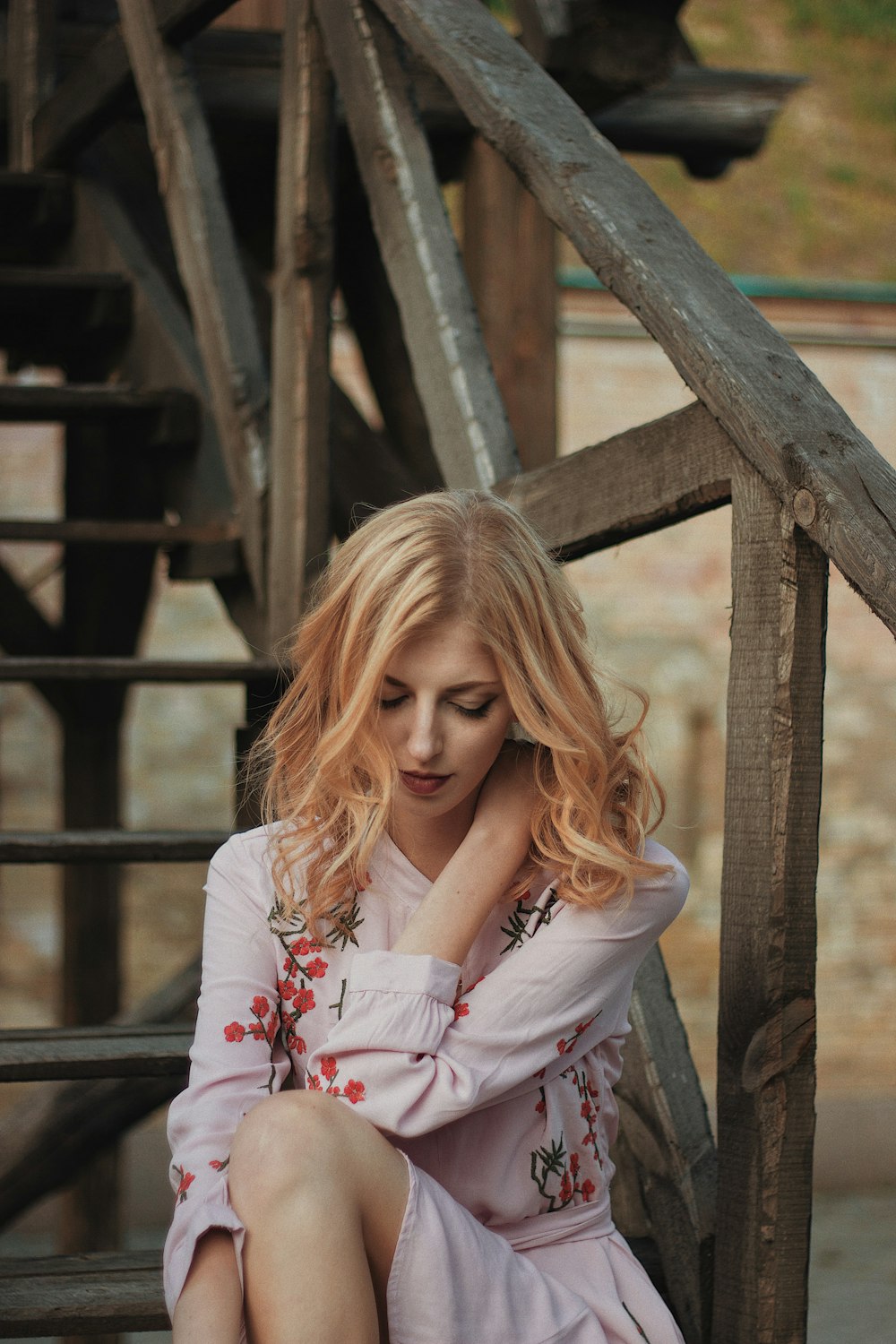 woman wearing white and red floral long sleeved dress sitting on stairs