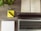 A wooden desk displays an open planner, a laptop, a notepad, a yellow sticky note with a pen, and a small potted plant. The planner is dated December 2016 and lies open to a week view. The laptop is positioned towards the bottom of the image with its keyboard visible.