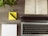 A wooden desk displays an open planner, a laptop, a notepad, a yellow sticky note with a pen, and a small potted plant. The planner is dated December 2016 and lies open to a week view. The laptop is positioned towards the bottom of the image with its keyboard visible.