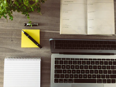 A beautifully arranged daily planner open on a wooden desk with colorful pens and a cup of coffee nearby.