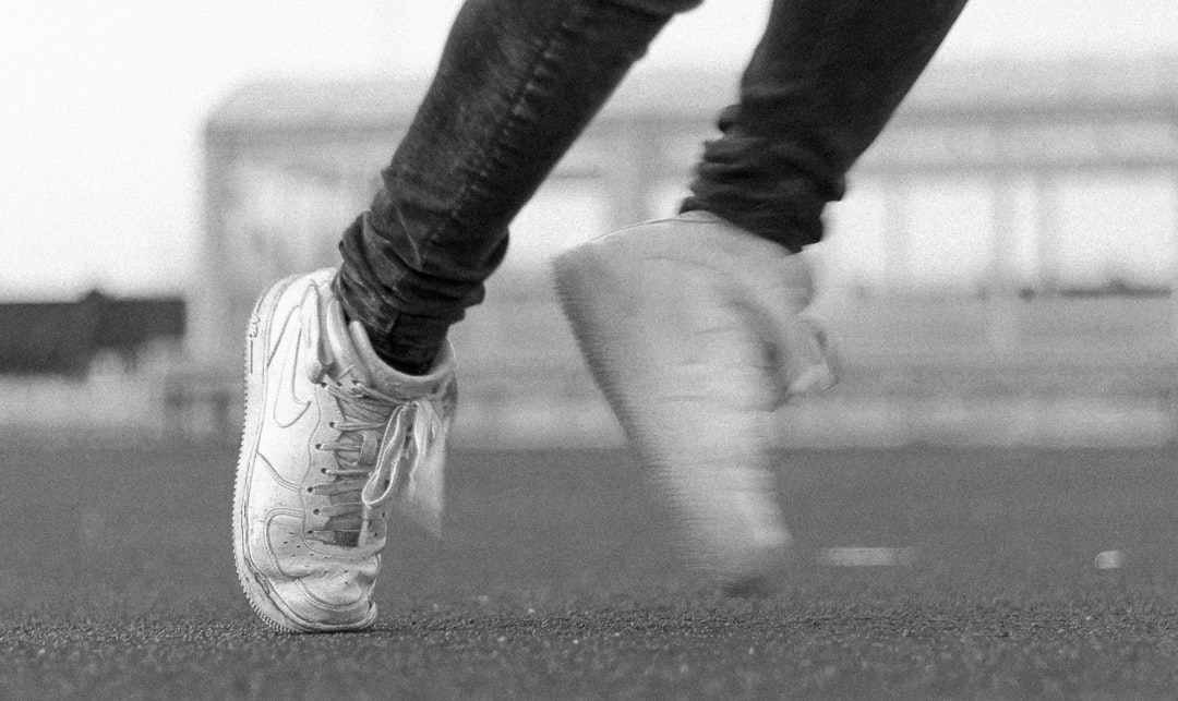 greyscale photo of person wearing Nike lace up shoes